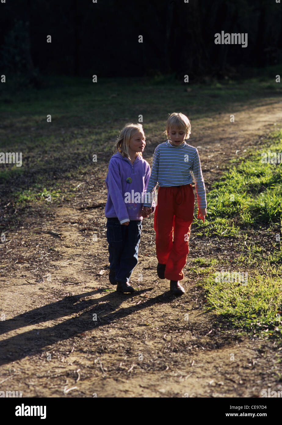 Young girls hand in hand walking on path Stock Photo - Alamy