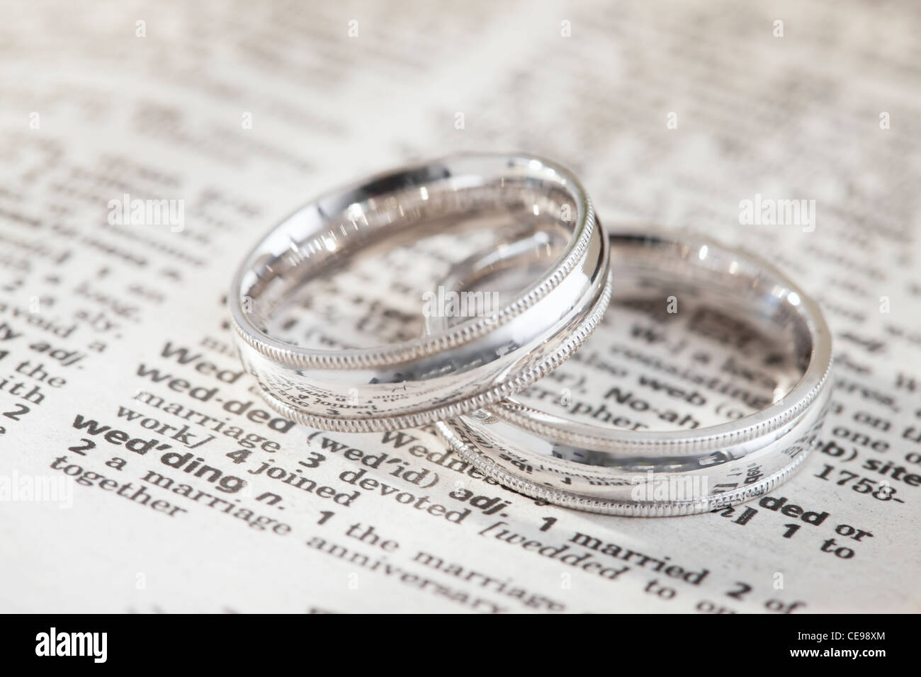 Close-up of silver wedding rings on dictionary page with 'wedding' definition Stock Photo