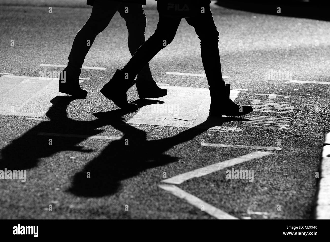 The legs of two females as they cross a road at a zebra crossing in London Stock Photo