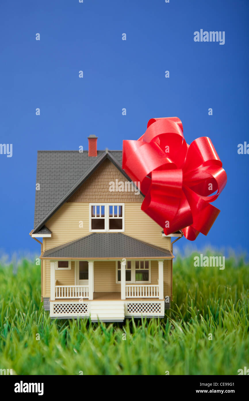 Model house with red ribbon on grass Stock Photo