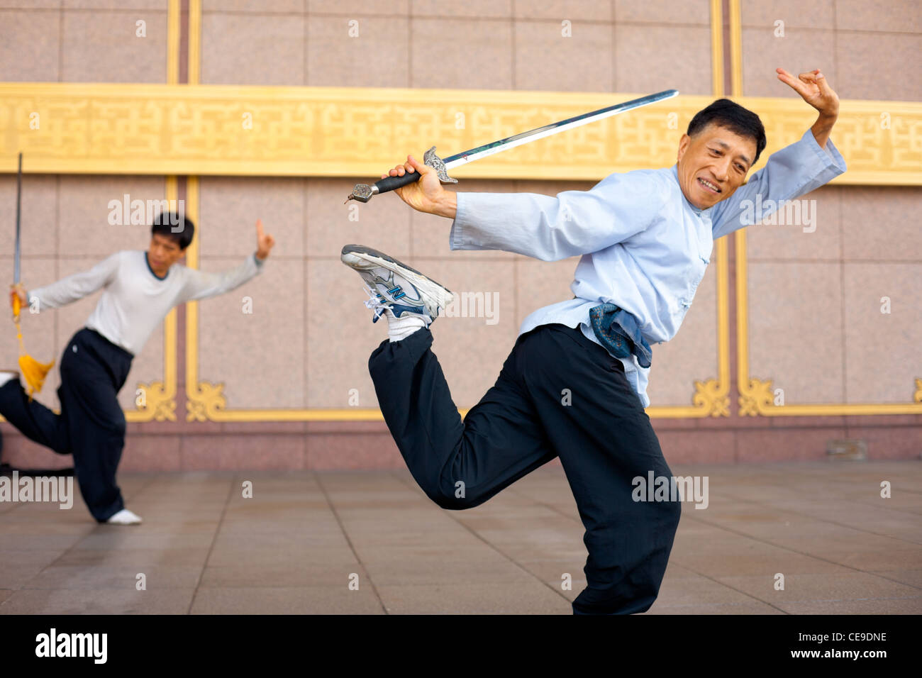 Two Taiwanese men in unison in a one legged Tai Chi Chuan stance with sword Stock Photo