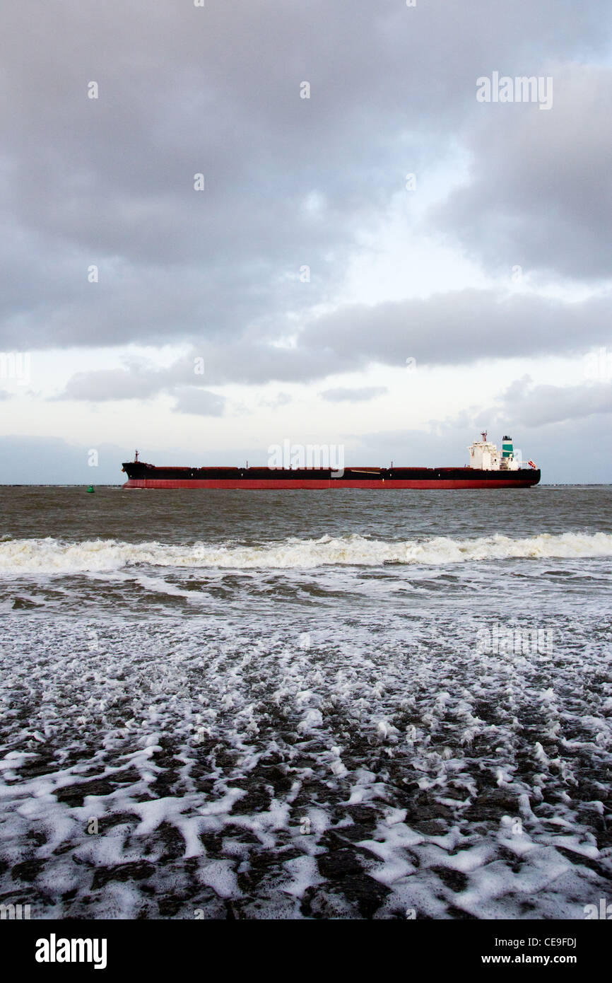Large oil tanker leaving Rotterdam harbor at sunset Stock Photo