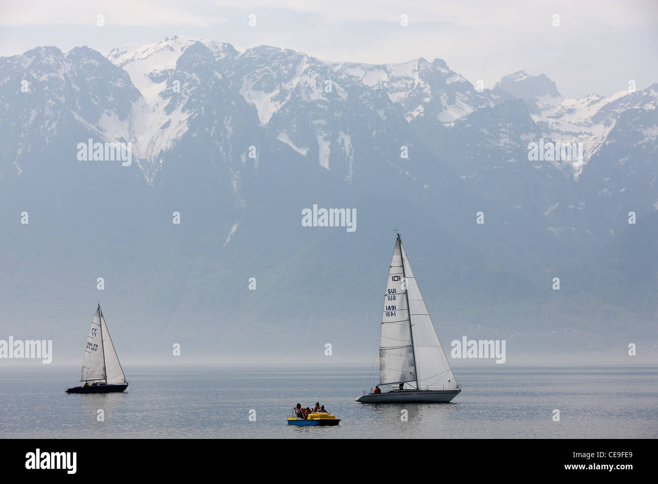 Sailboats on Lake Geneva. In the background you can see snowy peaks of the Alps. Stock Photo