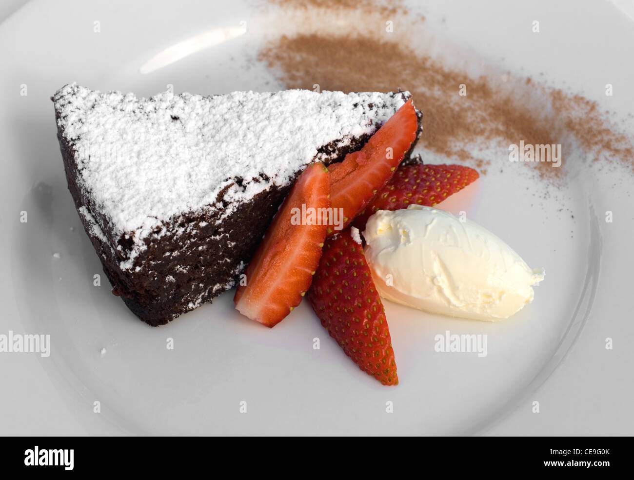 A Flourless Chocolate Tart, served with Strawberry Wedges and Creme Fraiche Stock Photo