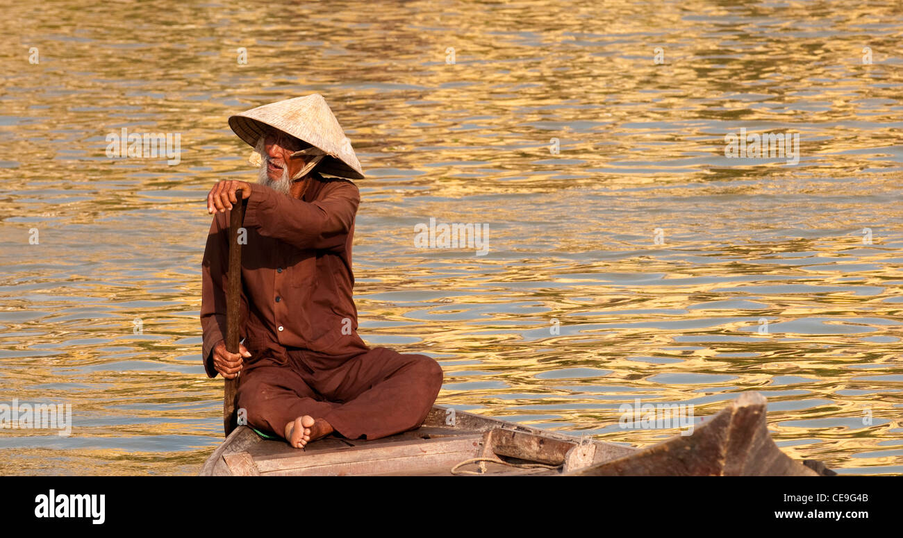 Vietnamese boatman in a small boat on the Thu Bon River, Hoi An, Viet ...