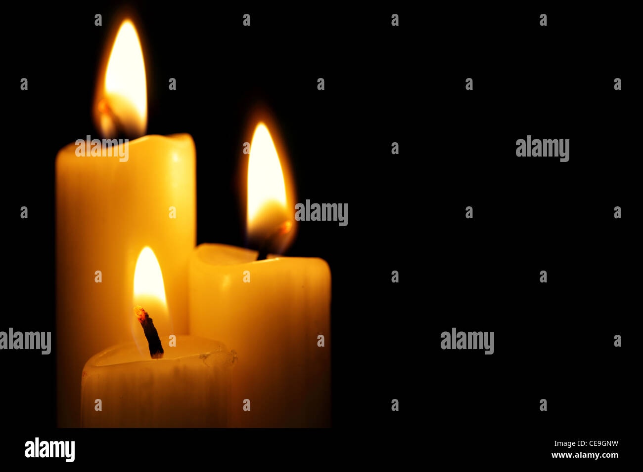 Three burning candles over a black background Stock Photo - Alamy