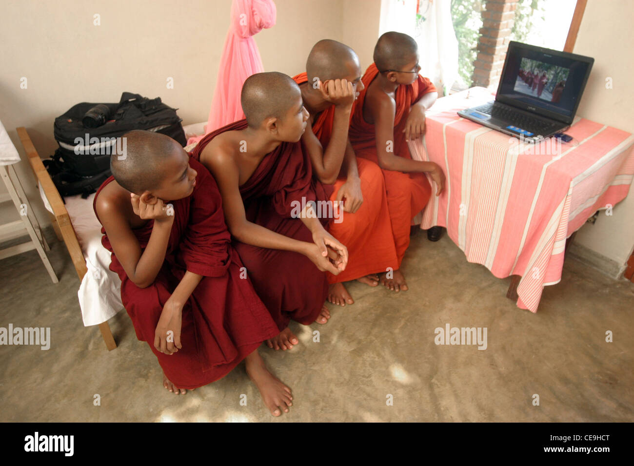 A group of young Buddhist Monks watch a slideshow of photographs taken by Photographer Ben Wyeth on a latop Stock Photo
