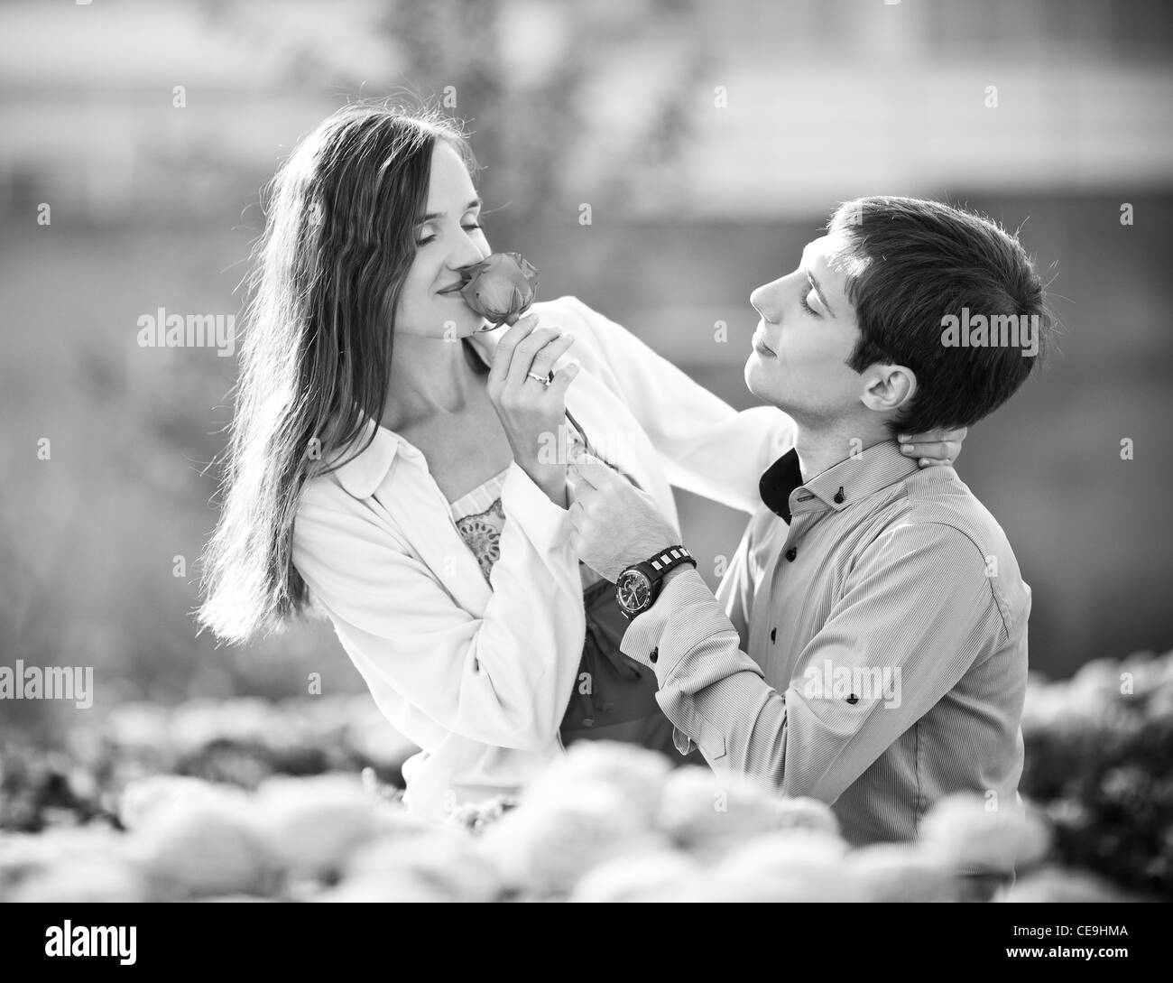 black and white image of a happy romantic young couple spending time outdoor in the autumn park (focus on the man) Stock Photo