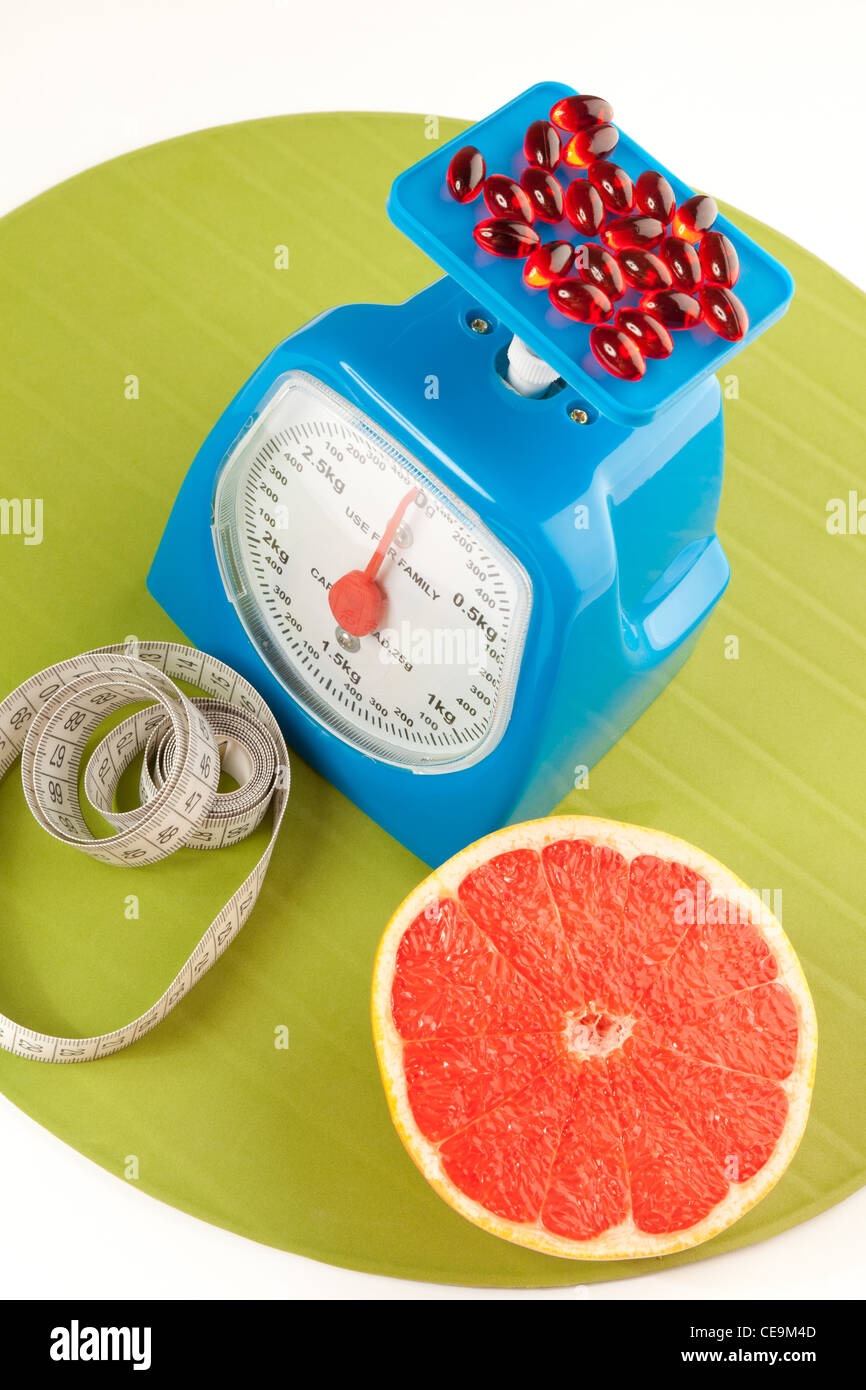 A picture of a grapefruit, pills, measure tape and scale Stock Photo