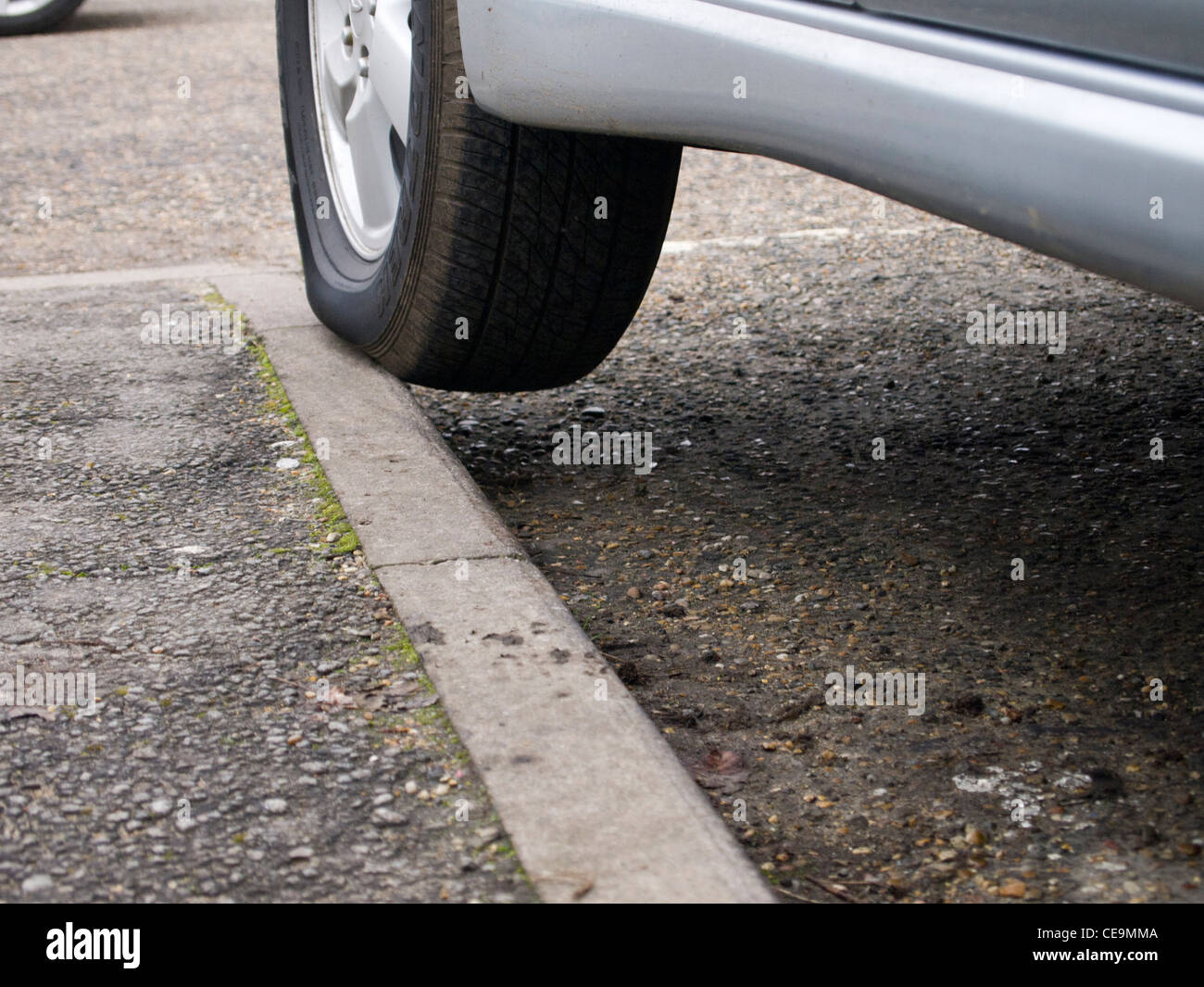 A parked car's wheel balanced on the edge of a curb Stock Photo Alamy
