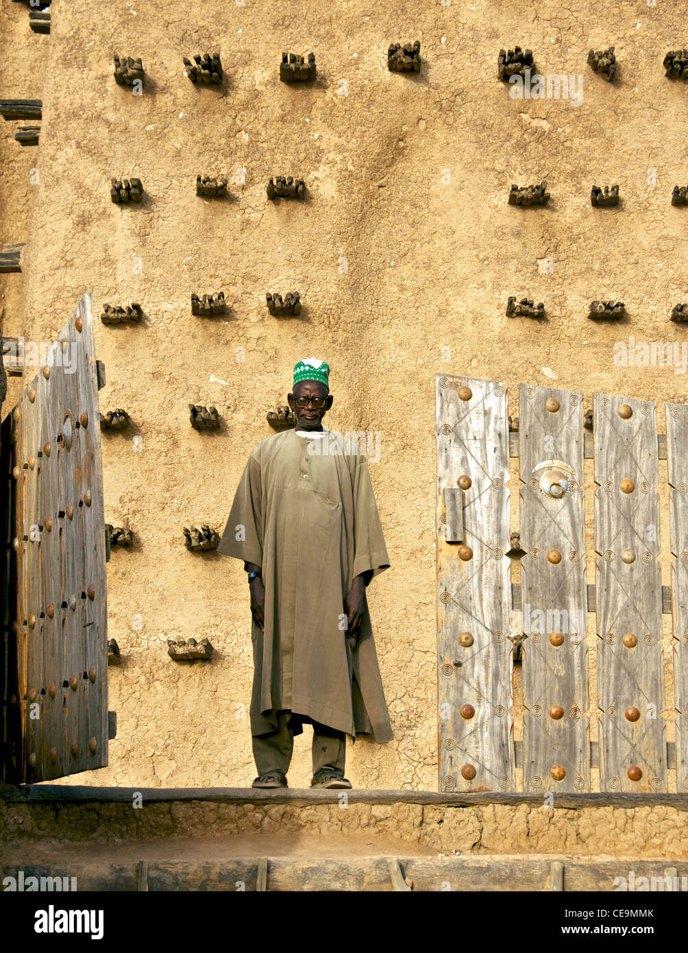 Man standing in front of the Great Mosque in Djenne, Mali. Stock Photo