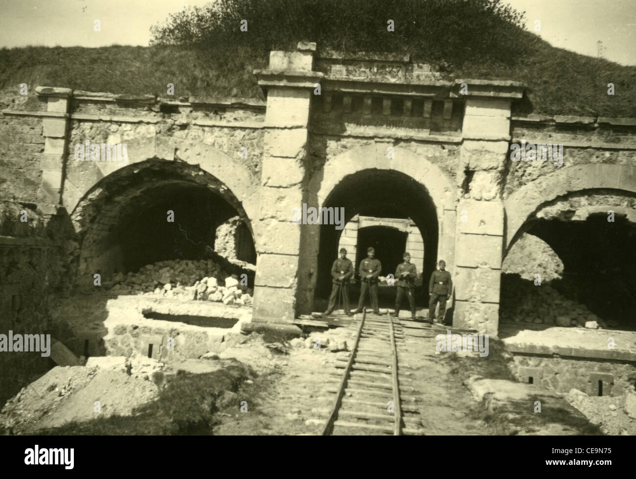 Nazi German soldiers standing on rail line leading to underground cave storage tunnel during WWII Stock Photo