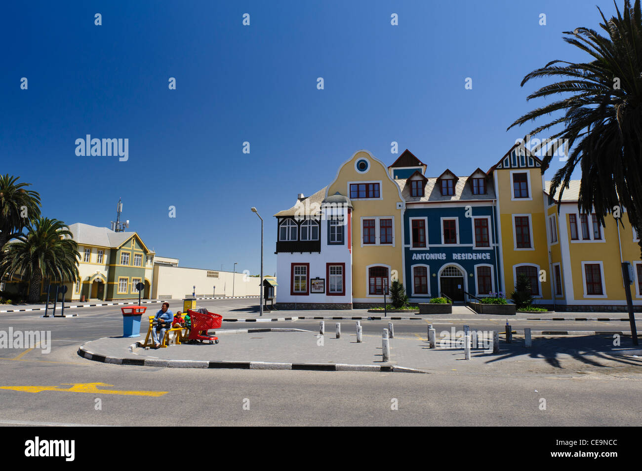 Mother, children, red shopping cart in front of Antonius Gebaude ( Residence) a former Franciscan hospital, Swakopmund, Namibia. Stock Photo