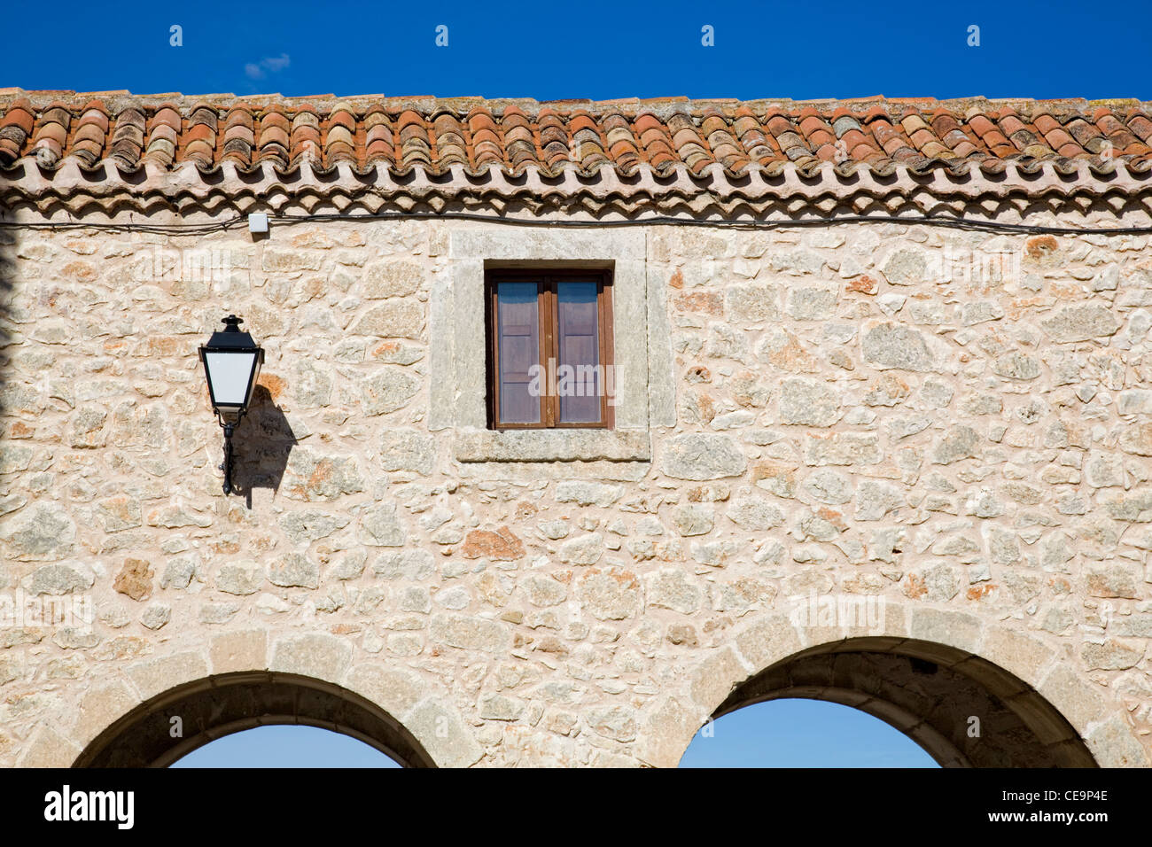 Facade made of stone, window, lamp and arches in a rustic house Stock Photo