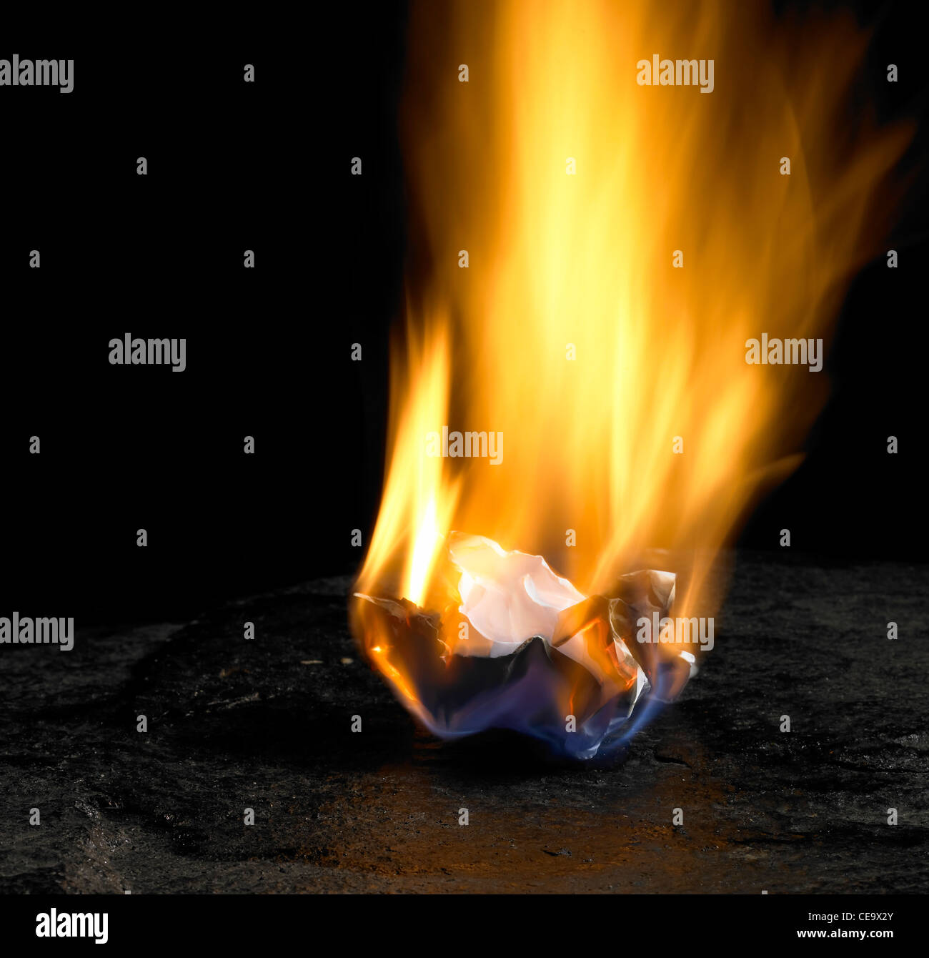 studio shot of burning rumpled piece of paper with big flame in dark