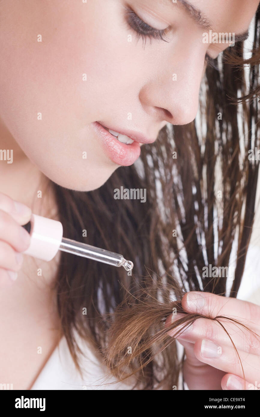 Woman applying hair serum Stock Photo - Alamy