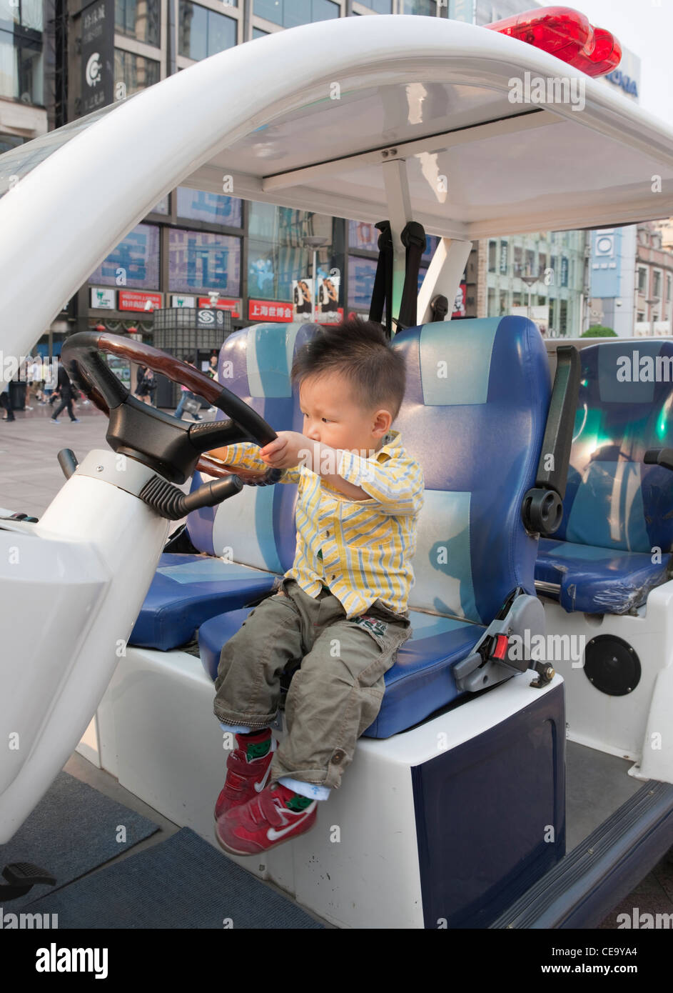 Child pretending to drive police car; Shanghai; China Stock Photo
