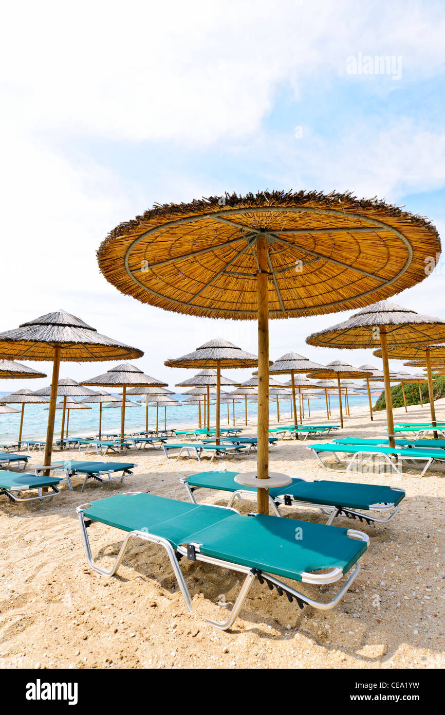 Umbrellas and lounge chairs on empty seaside beach in Greece Stock