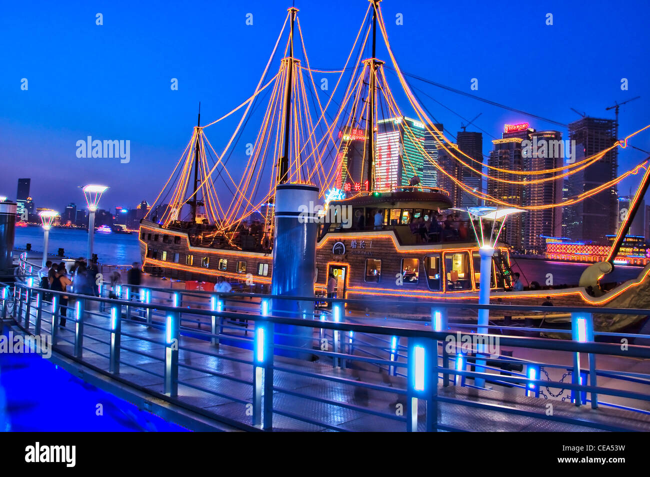 A boat at Huangpu river cruises dock by night - Shanghai, south Bund - China Stock Photo