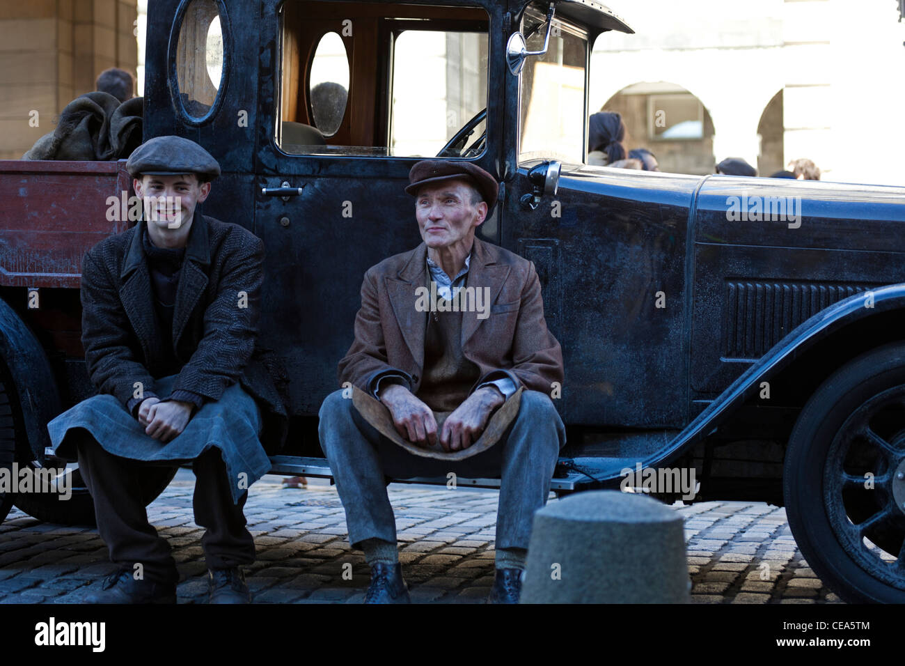 Man and boy in vintage outfits dressed as coalmen sitting on step of old fashioned truck Edinburgh Scotland UK Stock Photo