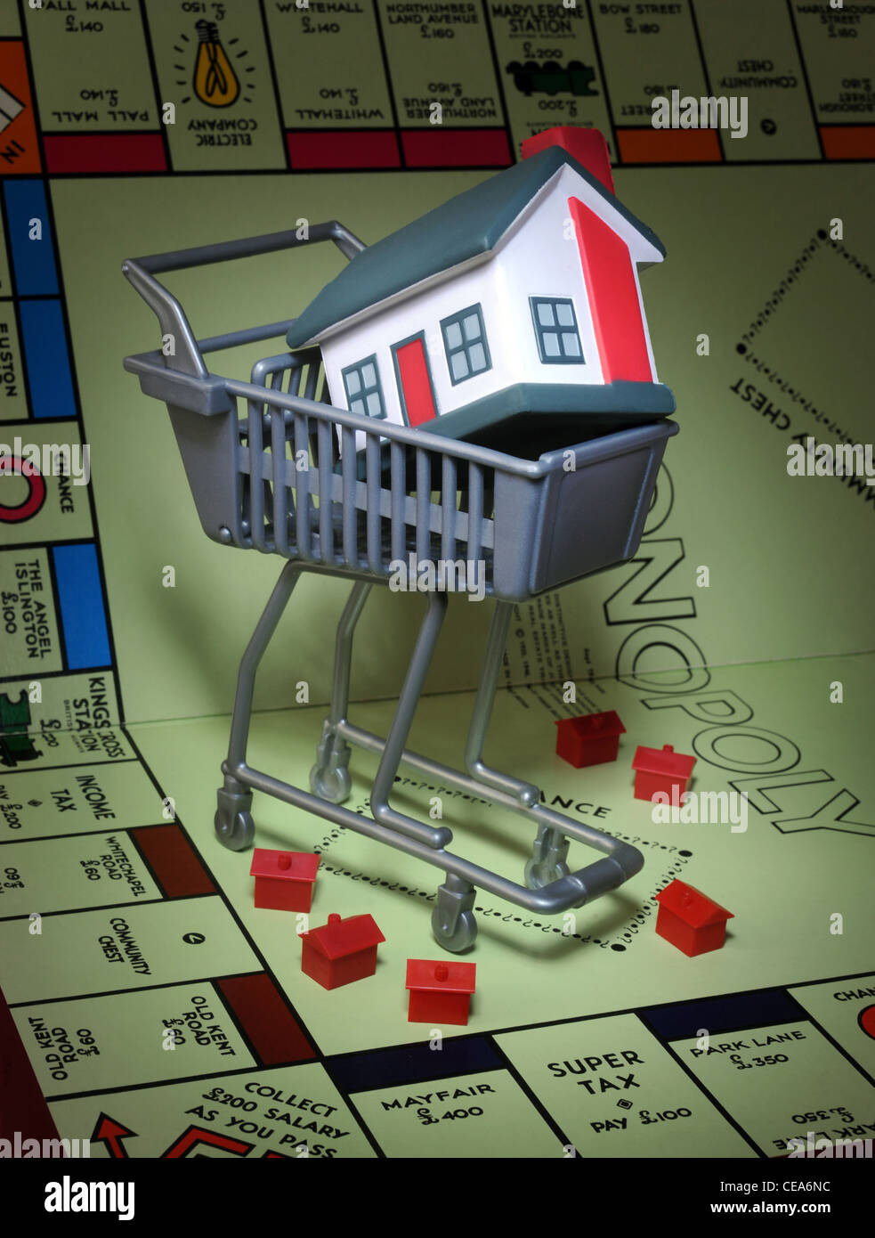 MODEL HOUSES ON MONOPOLY GAME BOARD WITH SUPERMARKET SHOPPING TROLLEY  RE HOUSE BUYERS BUYING PROPERTY MARKET PRICES HOMES UK Stock Photo
