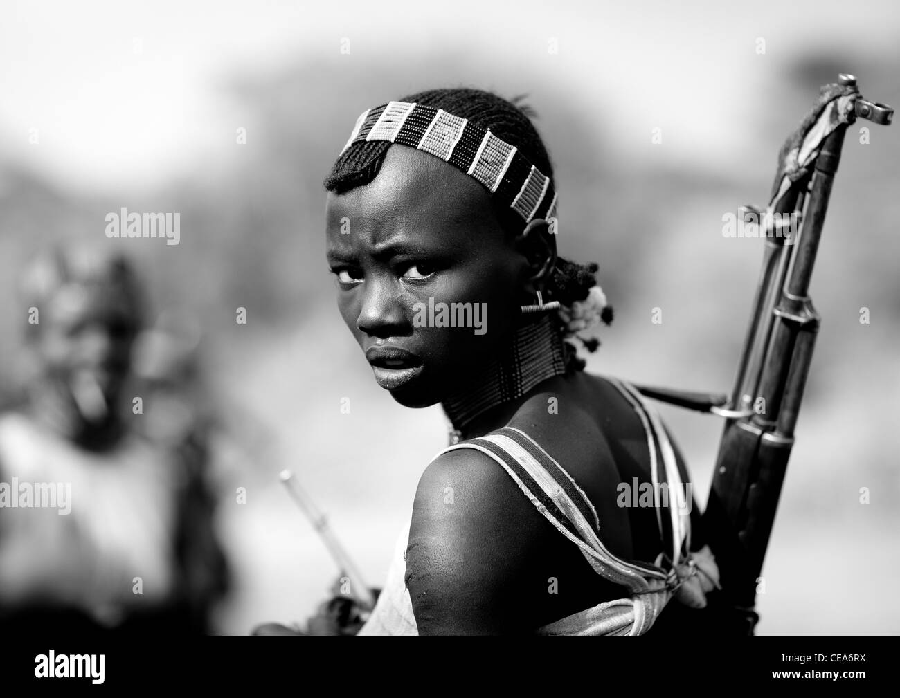 Young Hamer Woman With Beaded Headband And Kalashnikov Rifle On Back Omo Valley Ethiopia Stock Photo