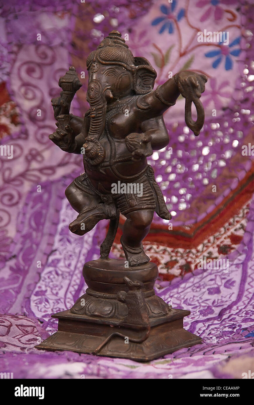 Bronze Ganesha dancing, on purple Rajasthani textile backdrop made from saris.  [Ganesha, the son of Shiva and Parvati, the elep Stock Photo