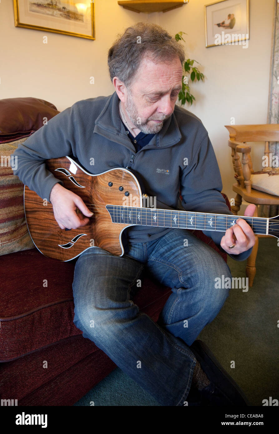 A middle aged man playing a Taylor acoustic guitar, UK Stock Photo