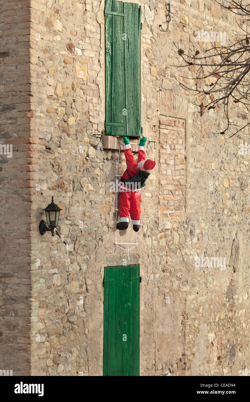 Inflatable Santa Claus climbing up a wall, Italy Stock Photo