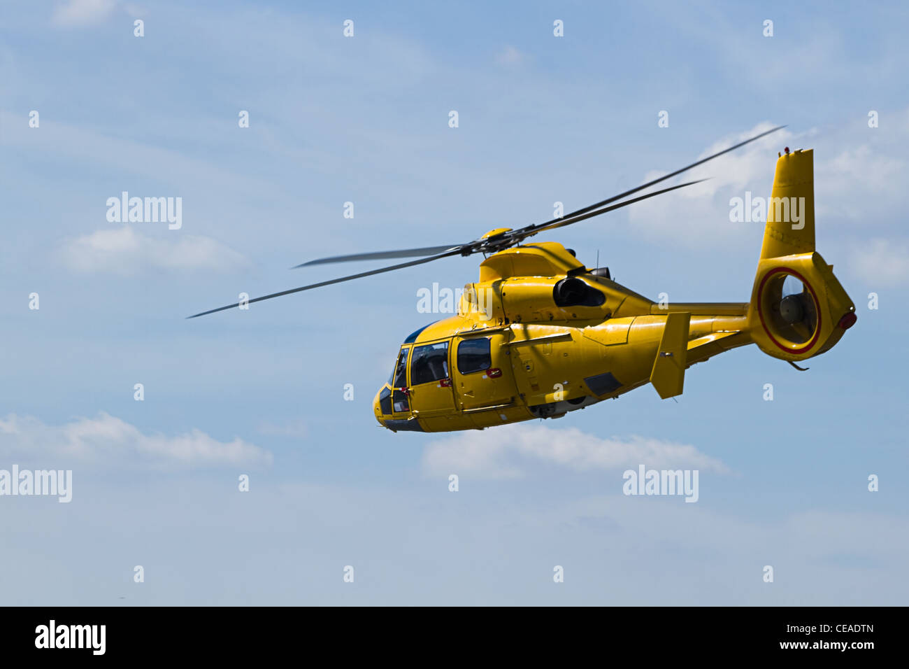 Yellow Helicopter flying in cloudy sky Stock Photo