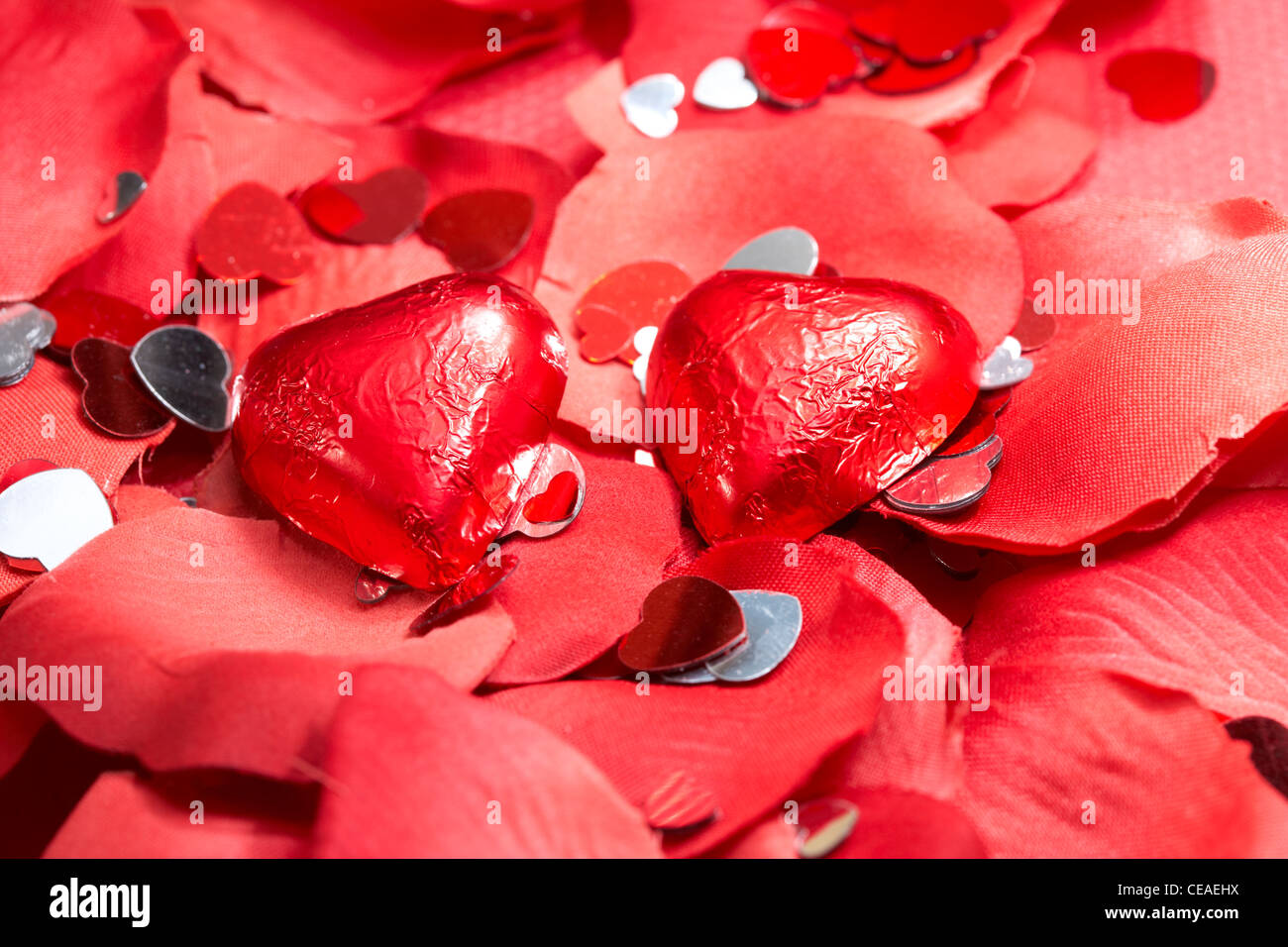 chocolate hearts on fake red petals with heart decorations Stock Photo