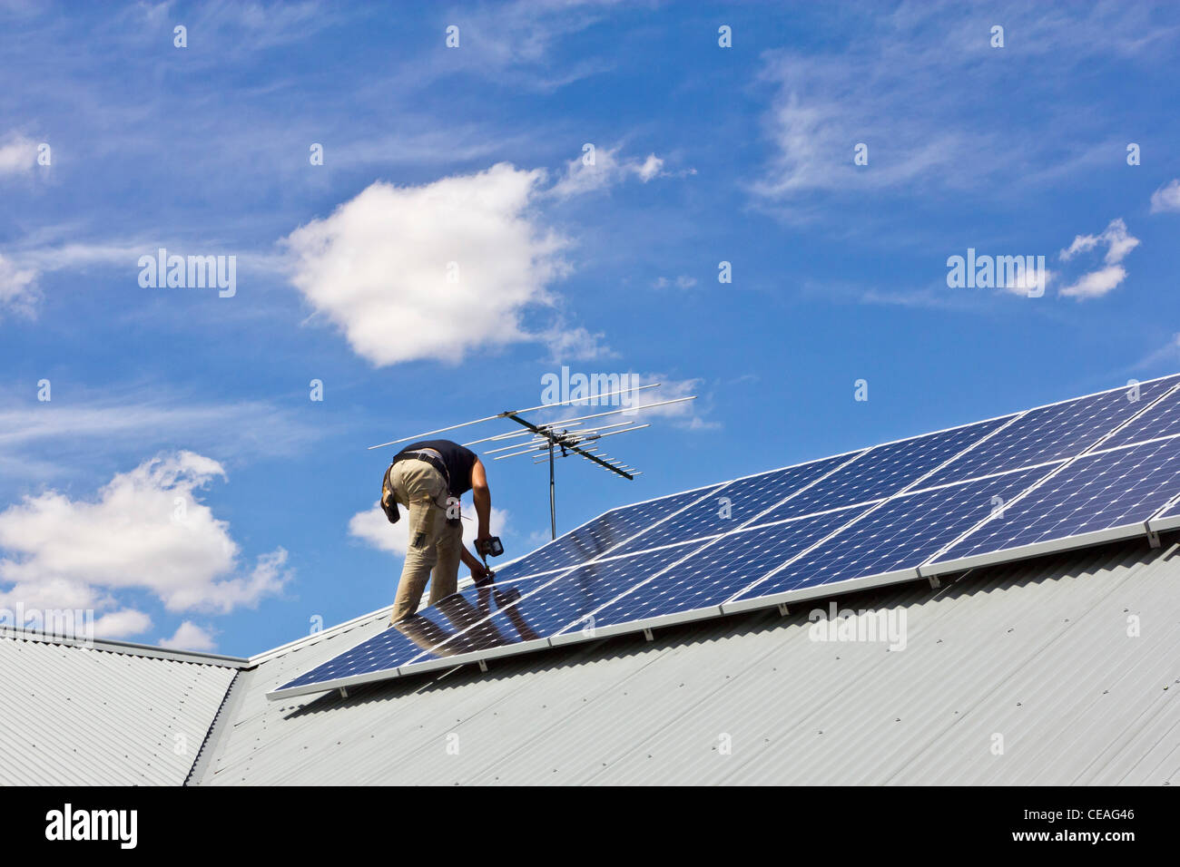 Workman installing Solar Power Panels on domestic roof Stock Photo