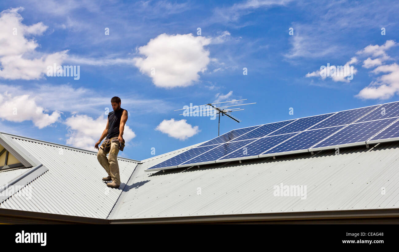 Workman installing Solar Power Panels on domestic roof Stock Photo