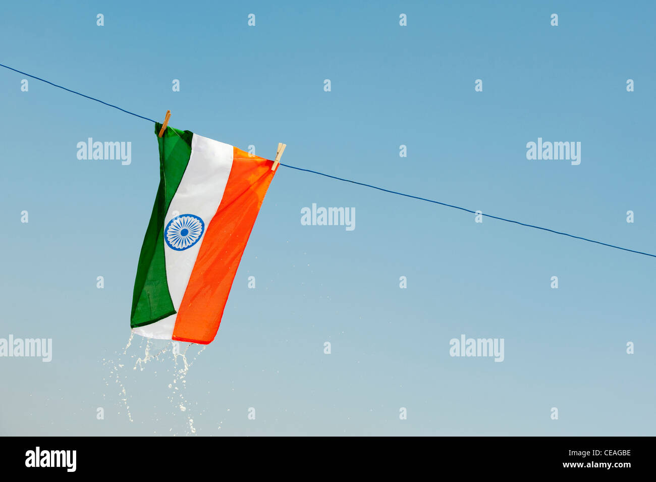 Wet dripping Indian flag on a washing line against a blue sky. Andhra Pradesh, India Stock Photo