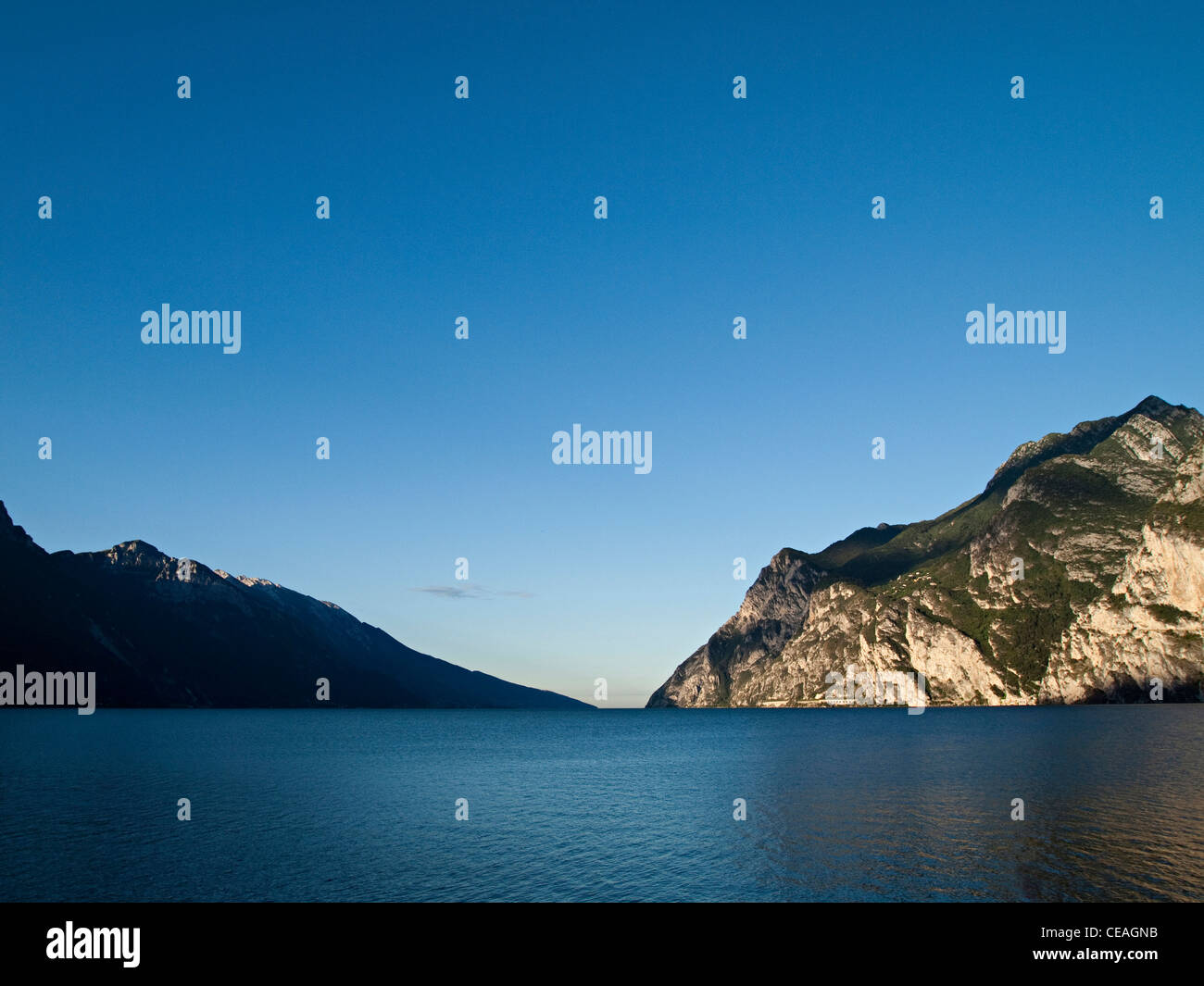 Tranquil morning at Lake Garda in northern Italy, big sky, mountains and calm water. Stock Photo