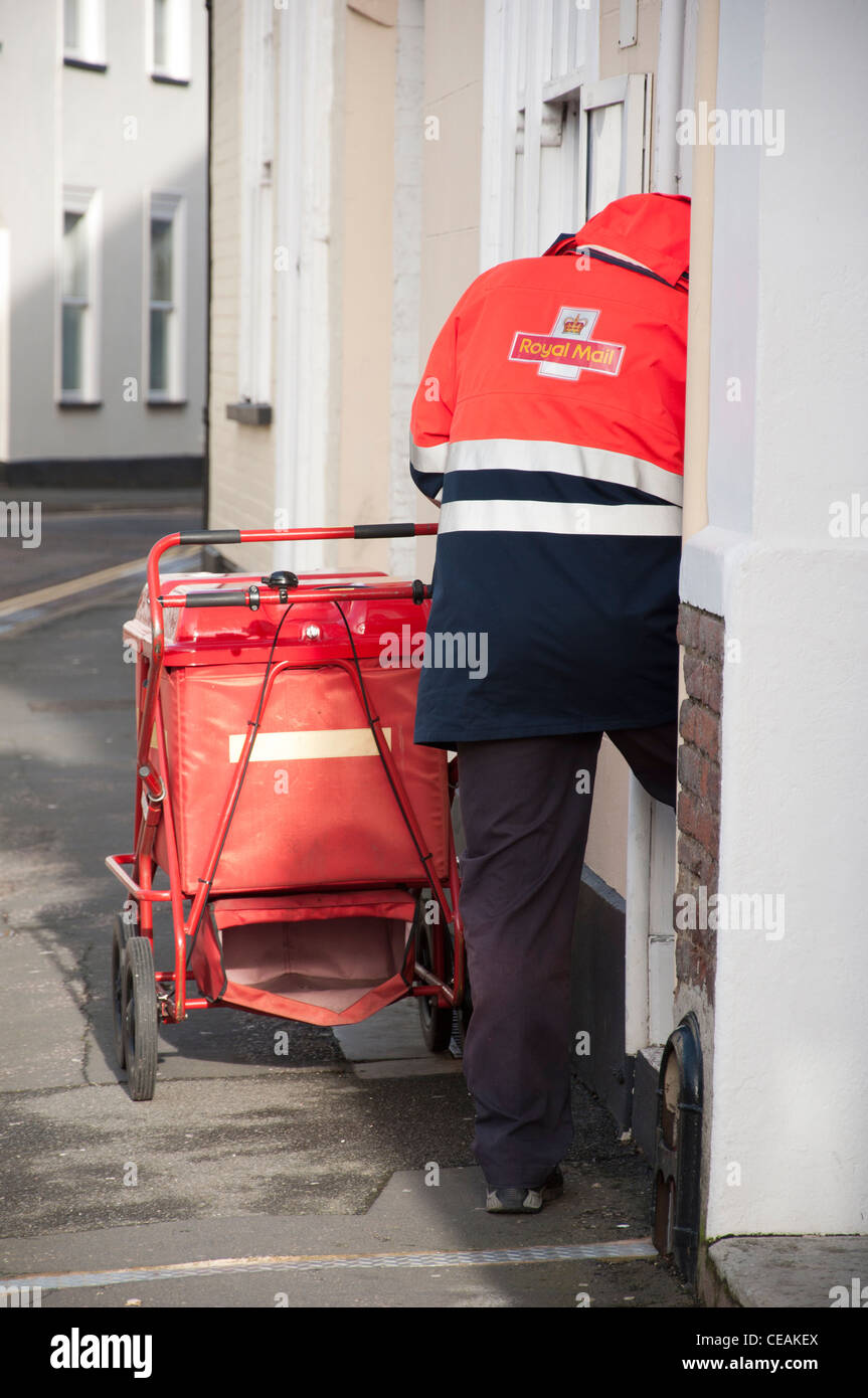 Royal Mail postman delivering letters with a trolley. Stock Photo