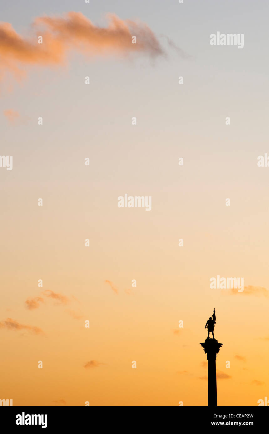 Statue on a pedestal and Orange Sky Stock Photo