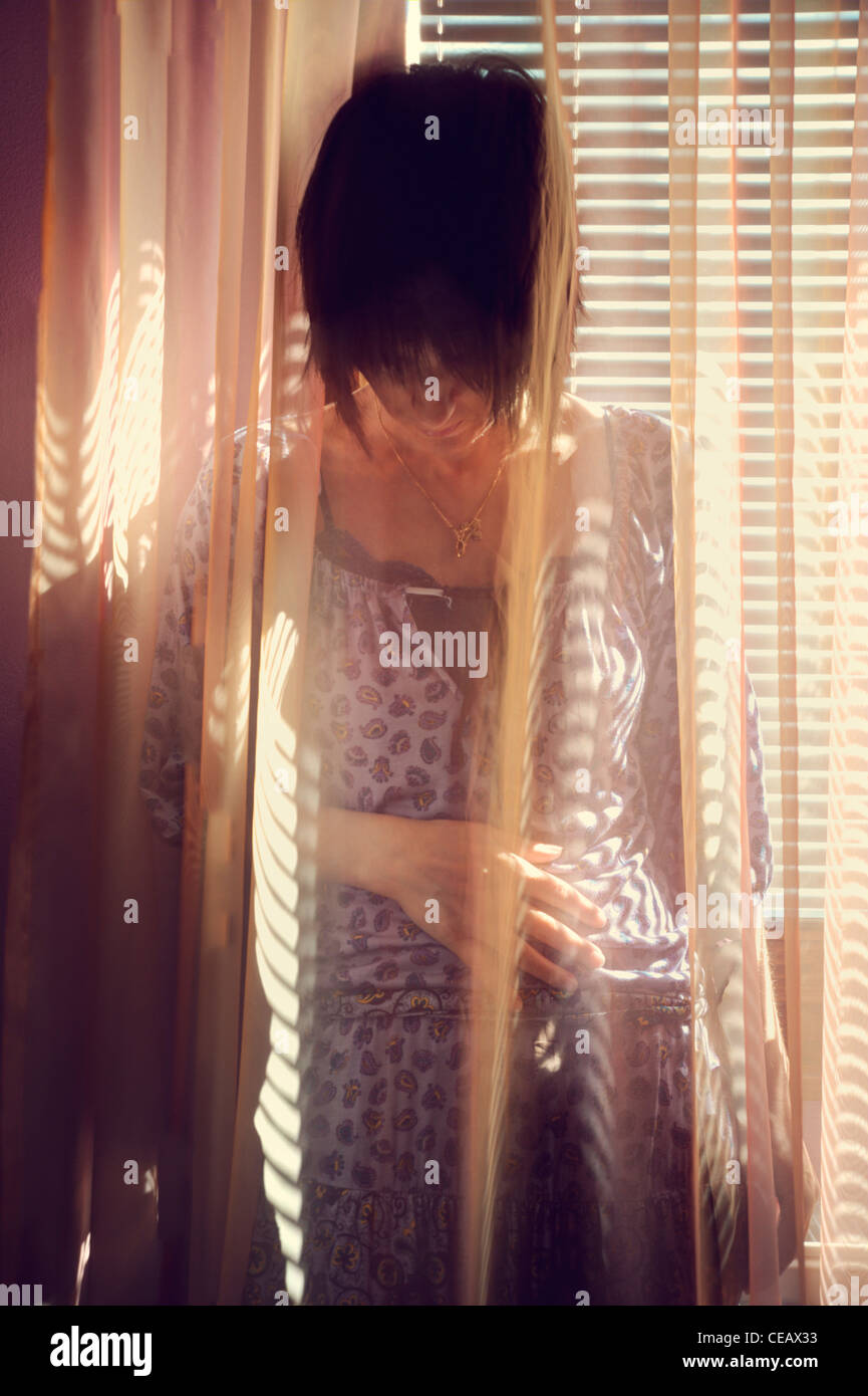 Portrait of a content young woman standing behind curtain Stock Photo