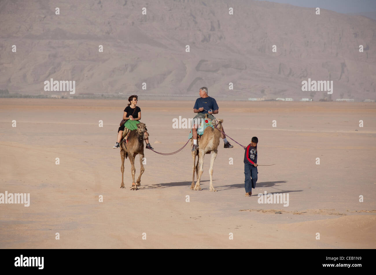 Jordan, Wadi Rum. Tourists riding camels across the desert sands of
