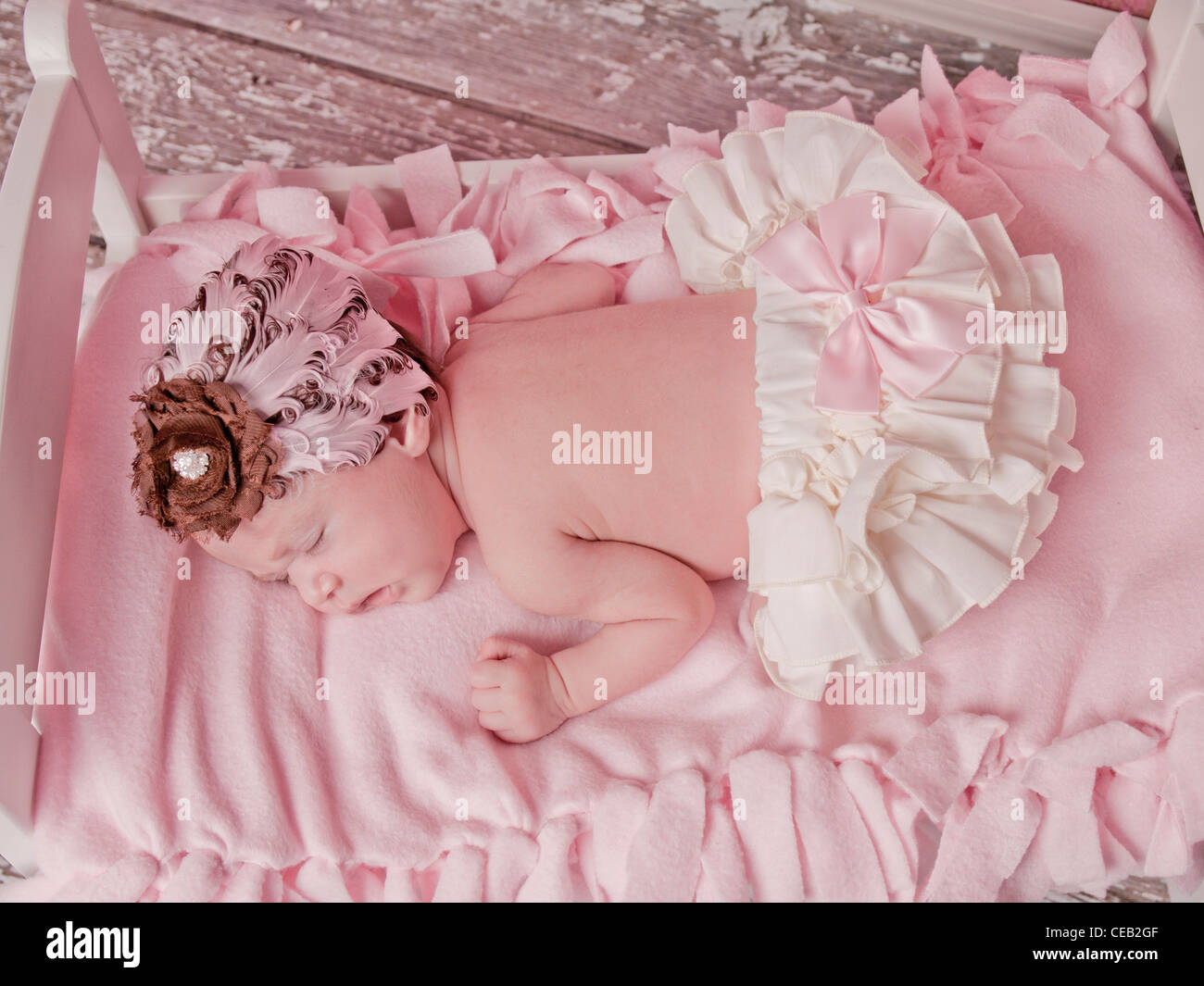 Beautiful newborn baby girl sleeping in her bed with a pink and brown