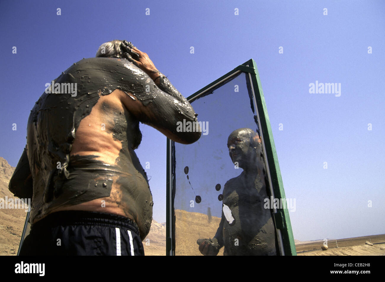 A man smeared with natural black mud from the Dead Sea at Ein Gedi Sea