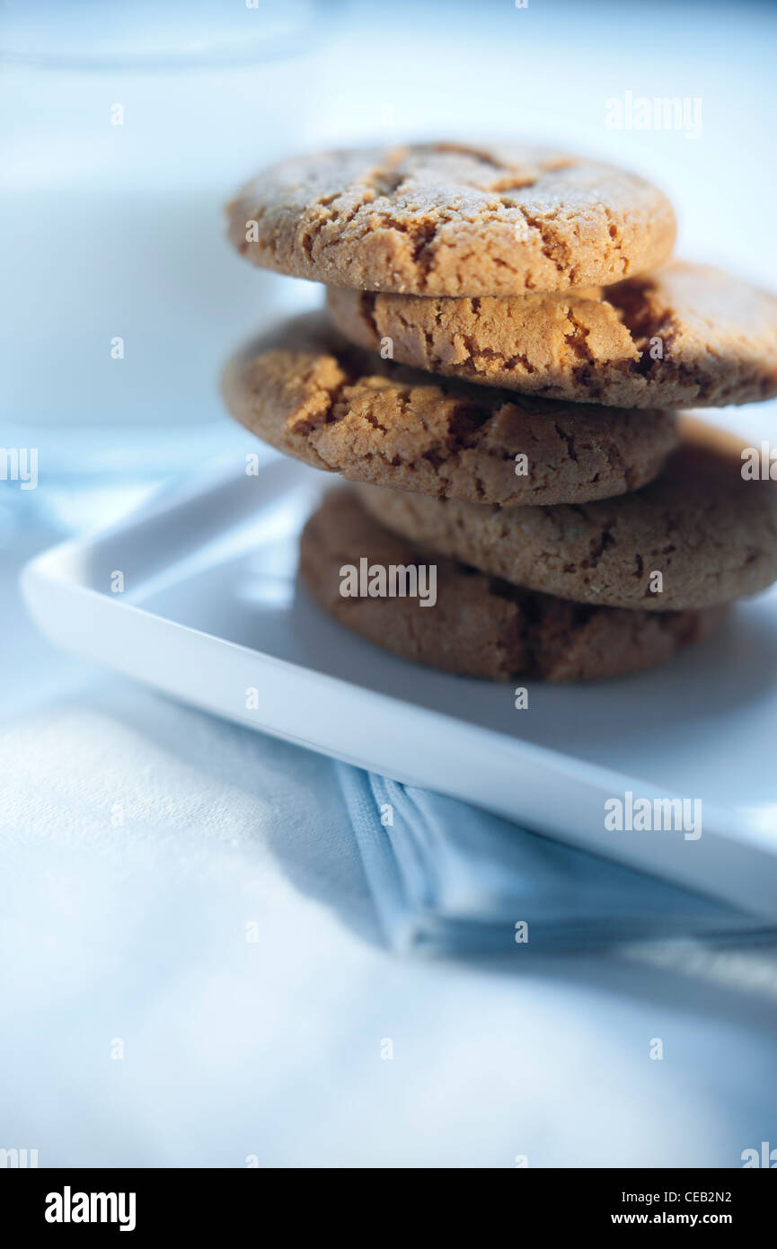 Ginger snap cookies (biscuits) served with a glass of milk on white table-ware. Stock Photo