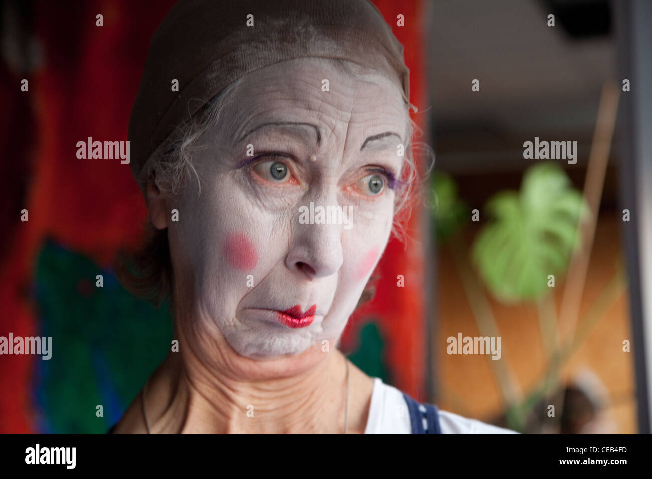 Elderly woman in whiteface clown makeup pulls series of funny faces. Picture 3 of 8 Stock Photo