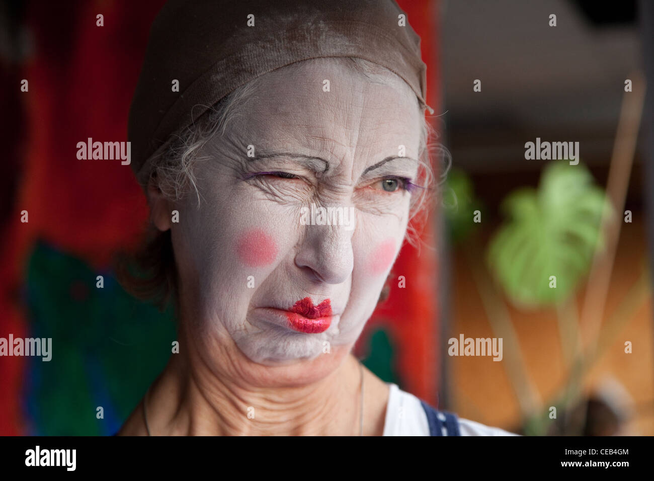 Elderly woman in whiteface clown makeup pulls series of funny faces. Picture 4 of 8 Stock Photo
