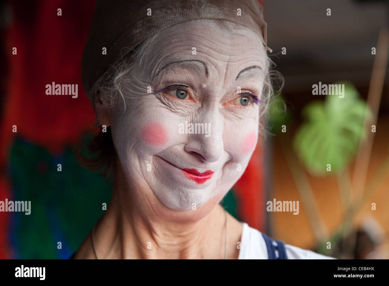 Elderly woman in whiteface clown makeup pulls series of funny faces. Picture 5 of 8 Stock Photo