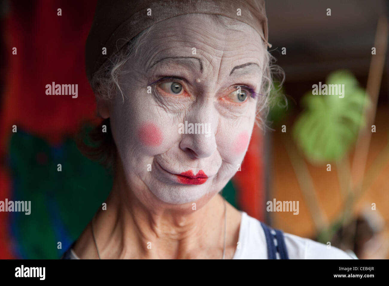Elderly woman in whiteface clown makeup pulls series of funny faces. Picture 6 of 8 Stock Photo
