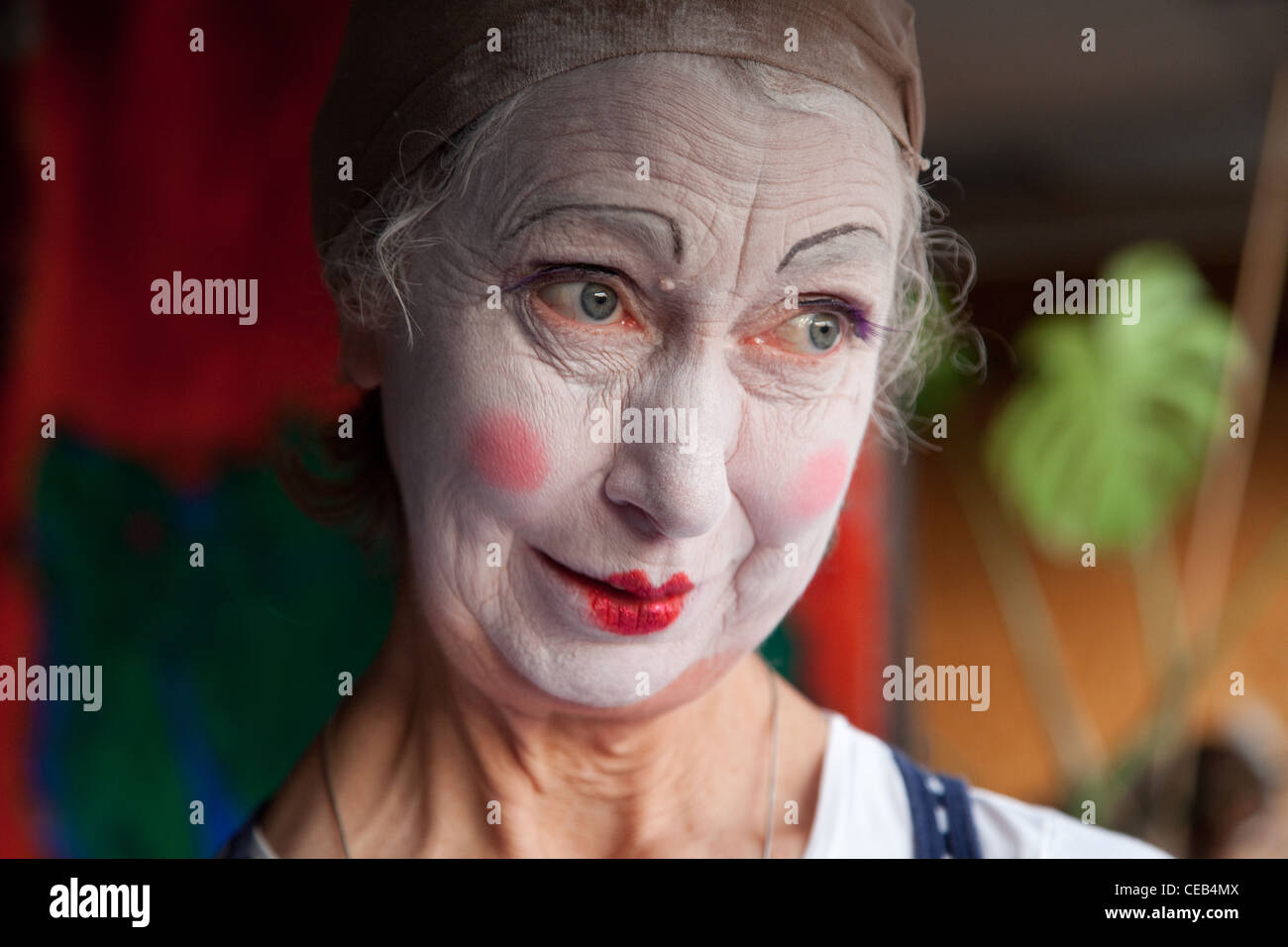 Elderly woman in whiteface clown makeup pulls series of funny faces. Picture 8 of 8 Stock Photo