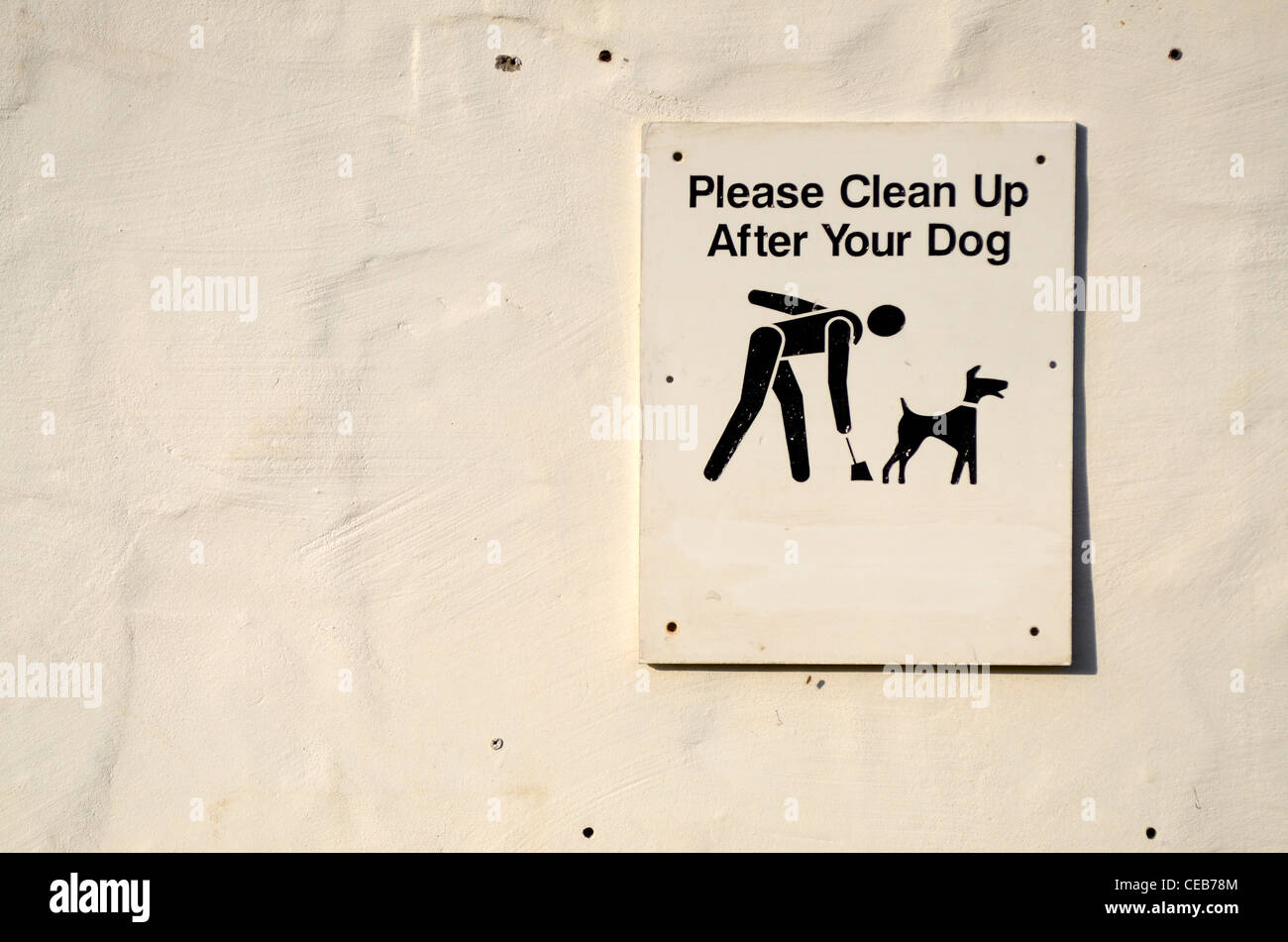 clean up after your dog sign white on white wall Stock Photo