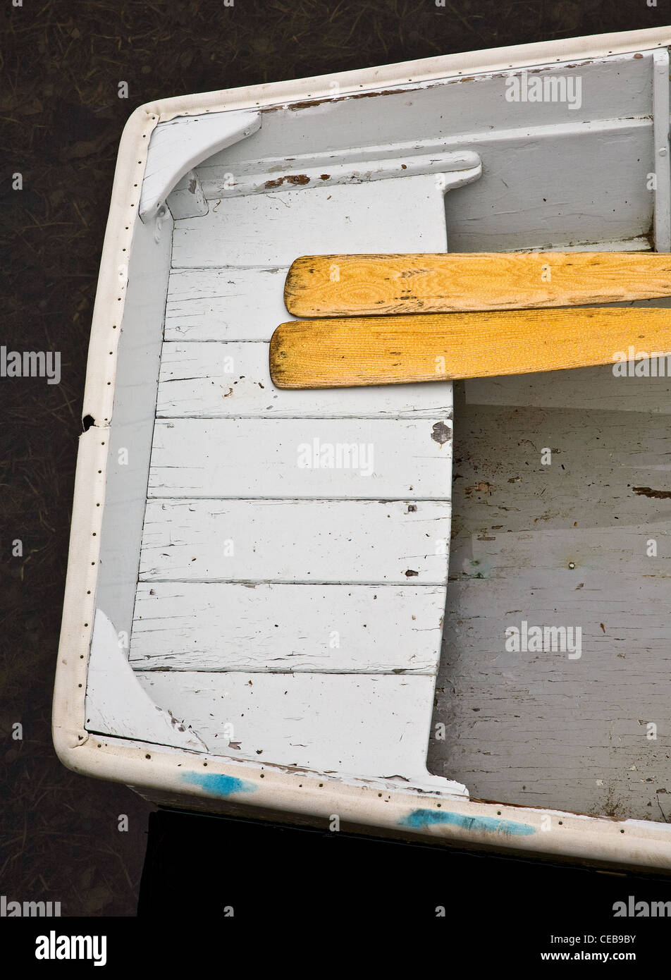Wooden boat floats peacefully with a pair of wooden oars at resting against the stern Stock Photo