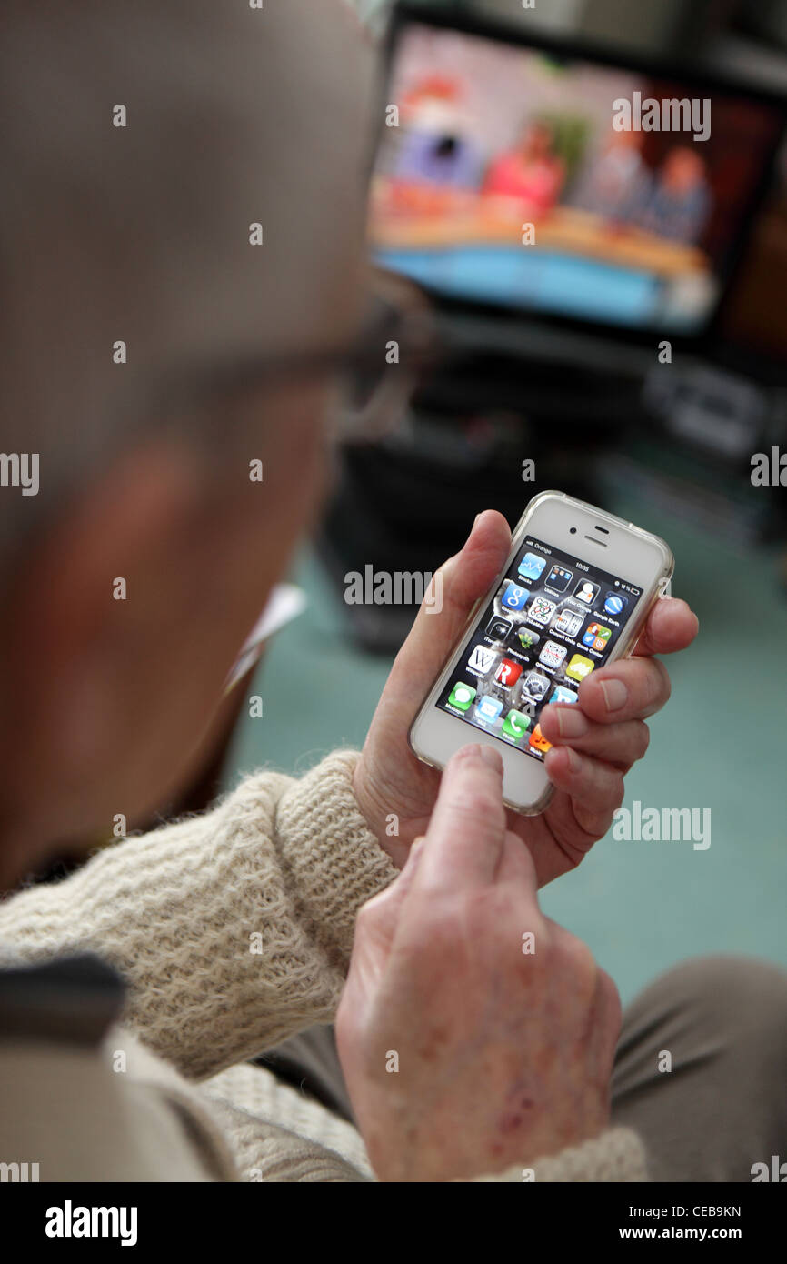 elderly older man adopting using enjoying new technology, iPhone 4S, Smartphone, intuitive touchscreen at home Stock Photo